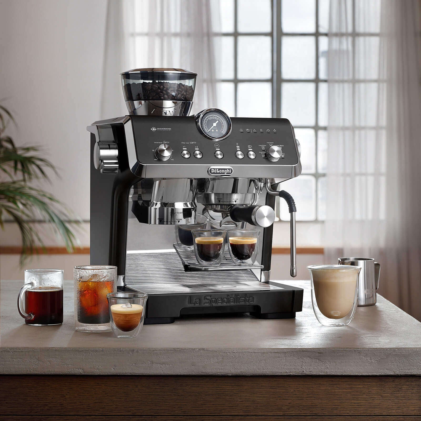 Espresso machine on a kitchen counter with coffee drinks and a cozy living room in the background.