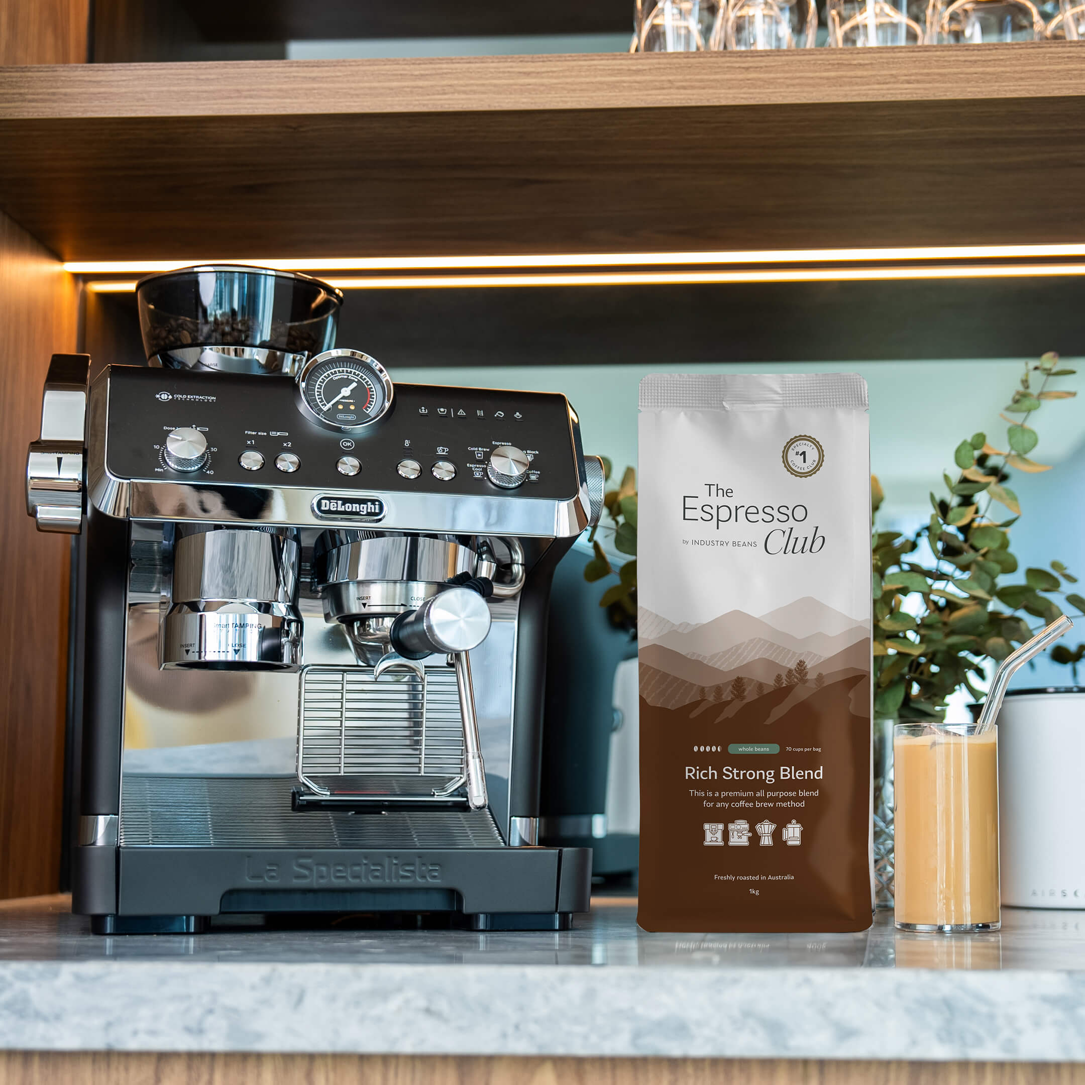 Bag of Rich Strong Blend on Bench with Coffee Machine and Iced Latte